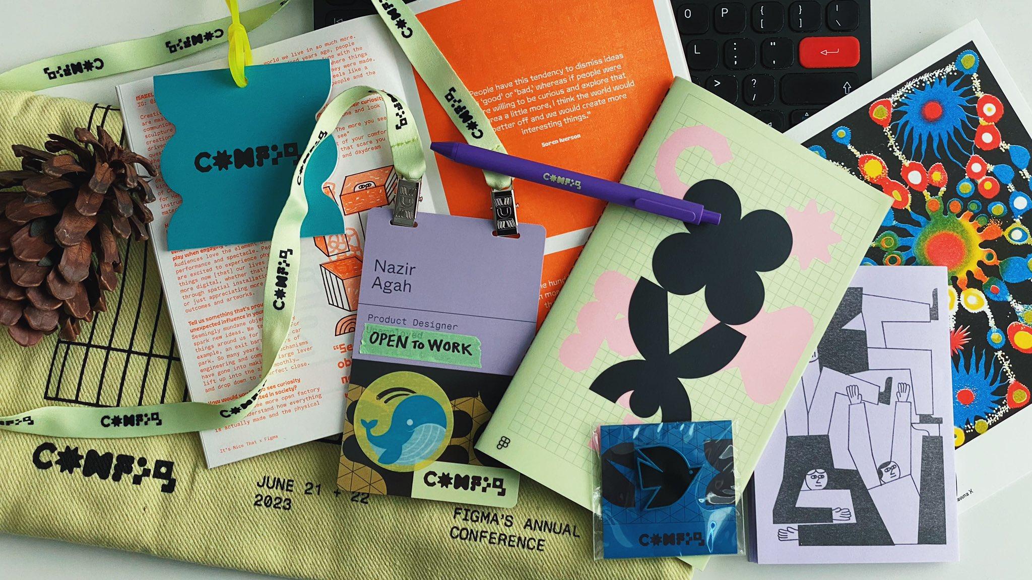 A photograph of the Config 2023 swag bag contents, including a notepad and pen, printed materials, a zine, and a name badge.