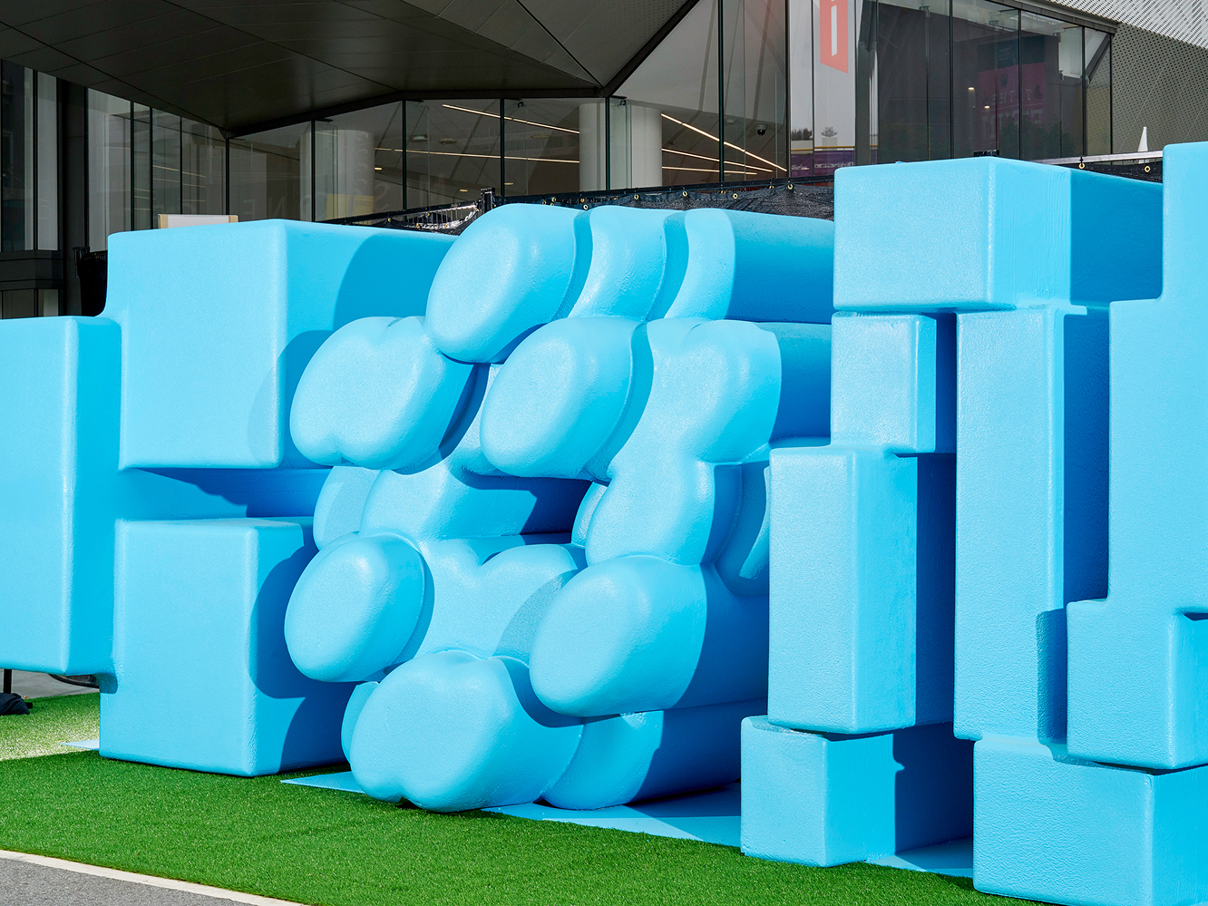 A close-up view of a blue sculpture Config logo that reveals blocky and bulbous forms 