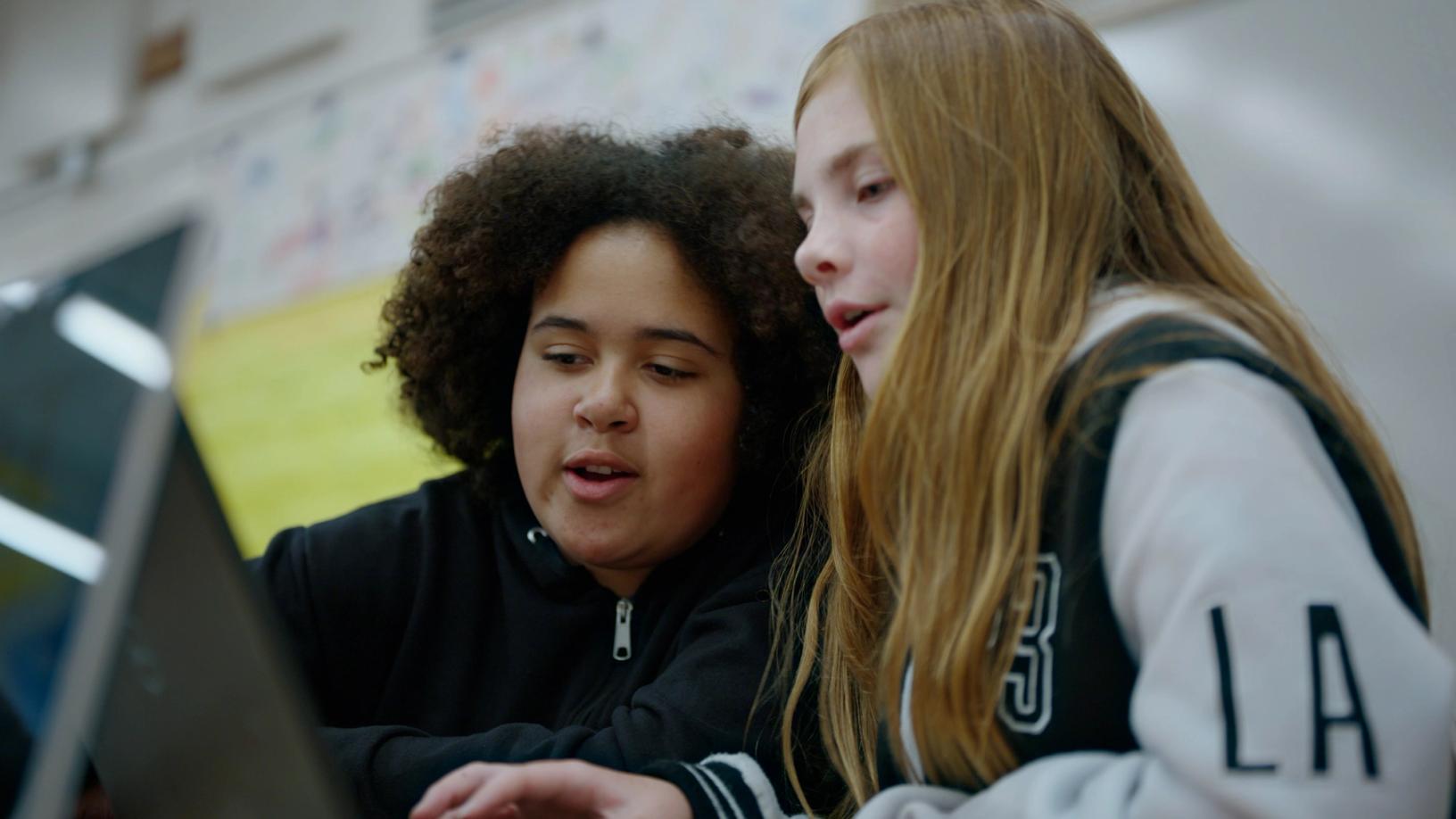 Students sit together beside a laptop
