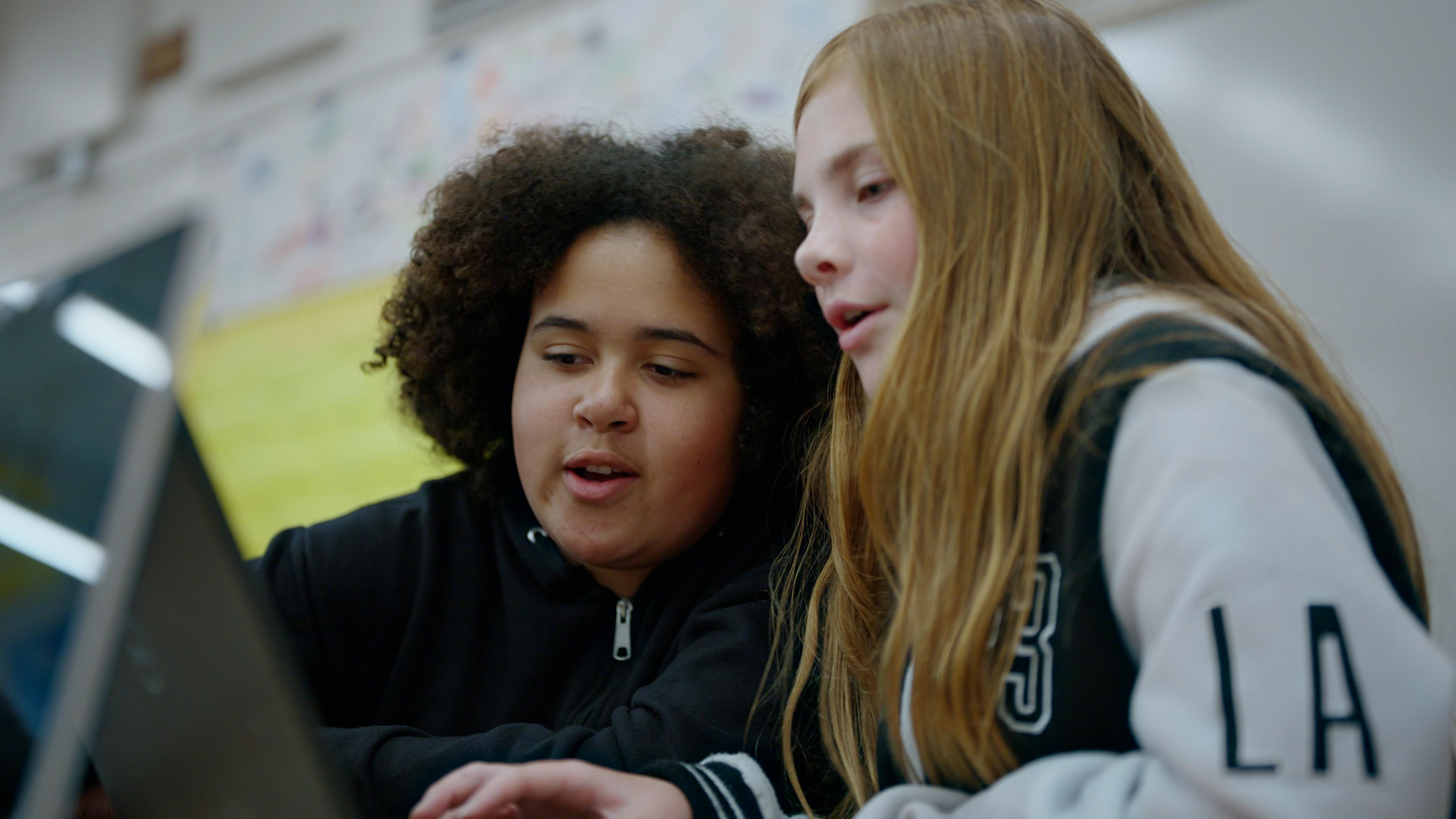 Students sit together beside a laptop