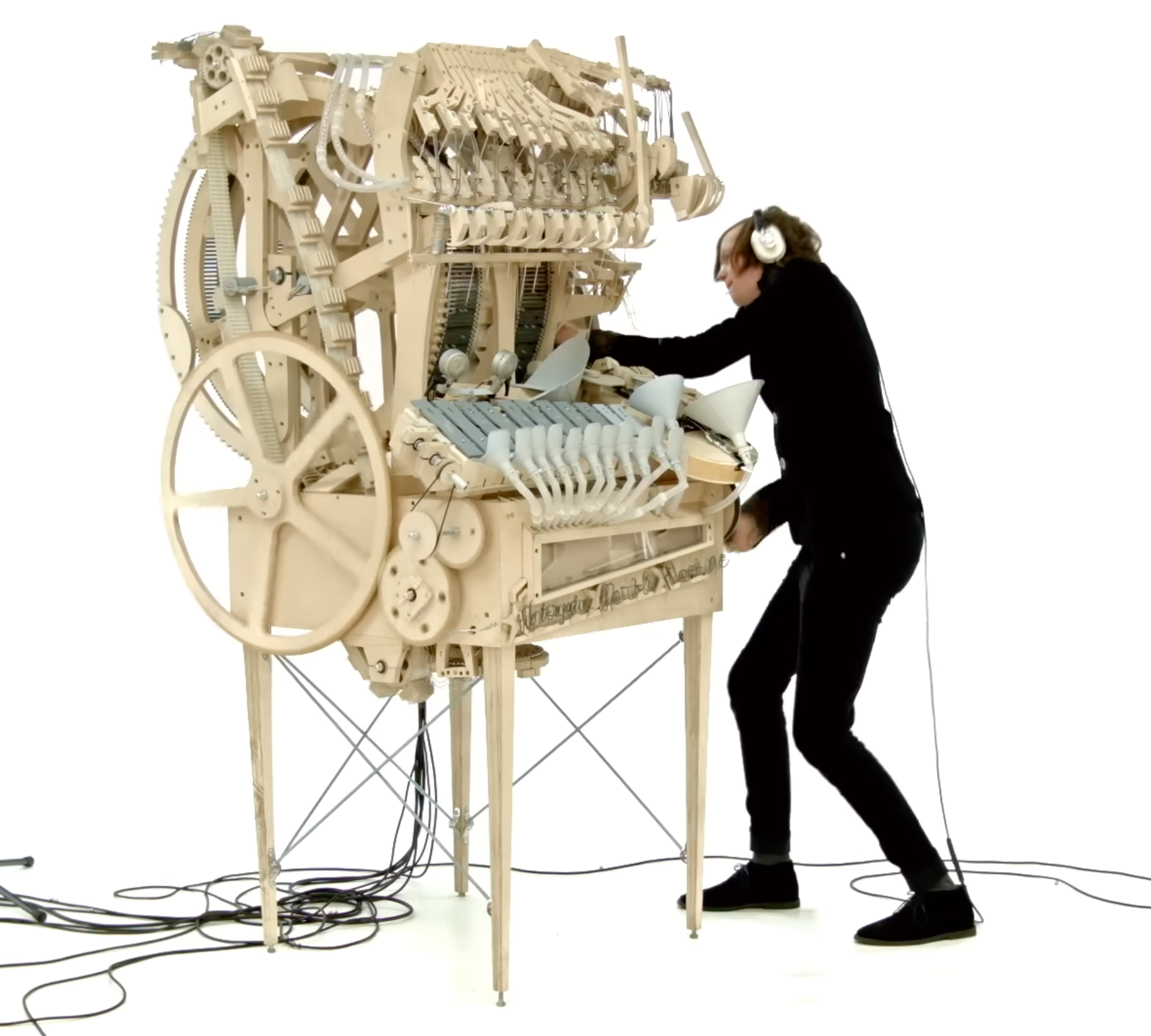 A man wearing all black plays a wooden instrument, showcasing his musical talent and passion for music.