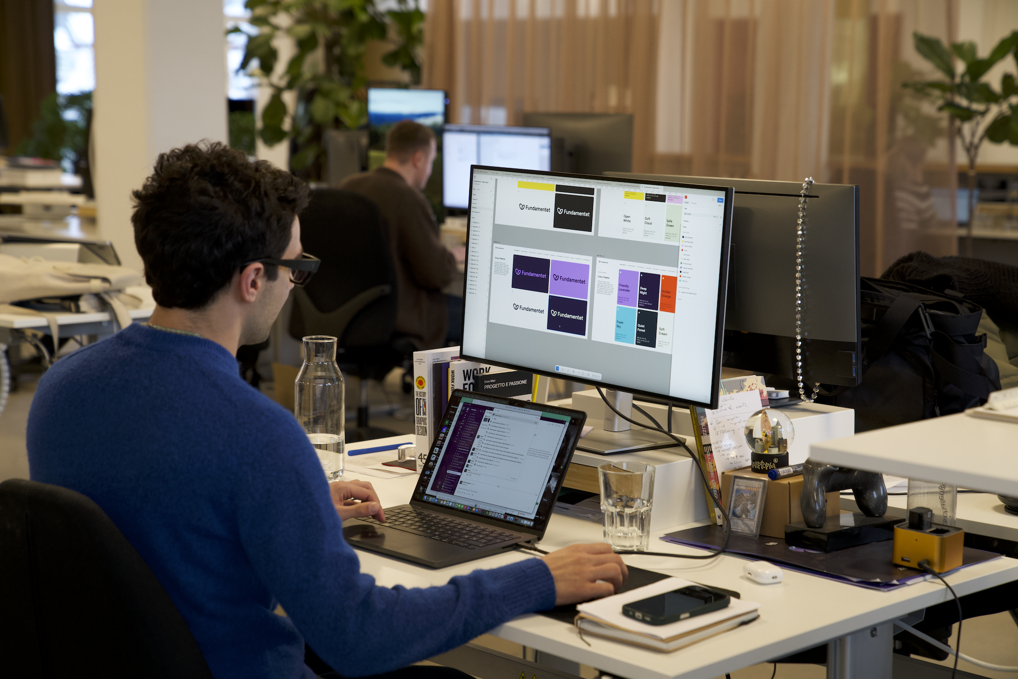 デスクでFigmaファイルに取り組んでいるKnowitの従業員。ノートパソコンと外部モニターを使用