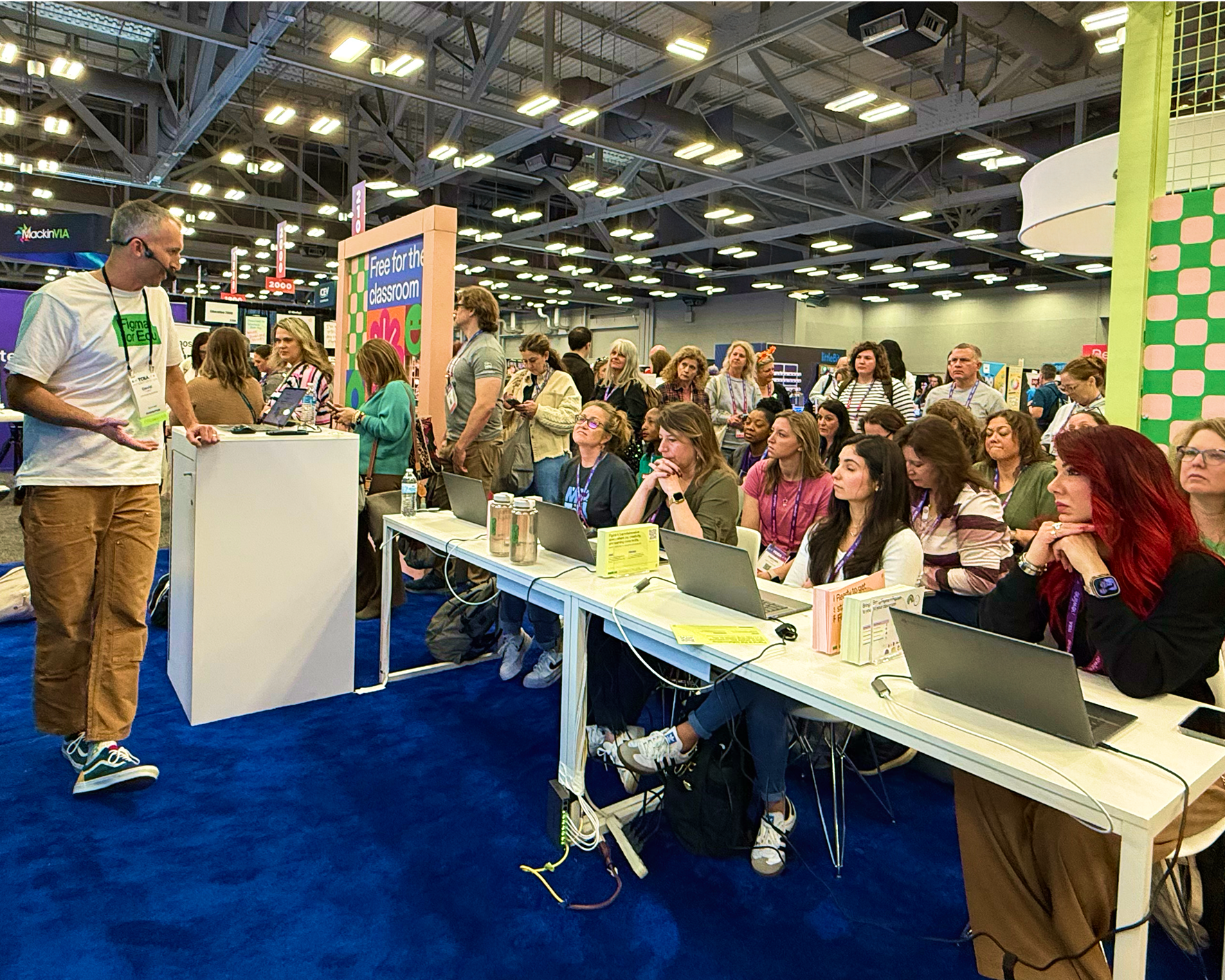 Education team member presenting to audience with laptops at a conference