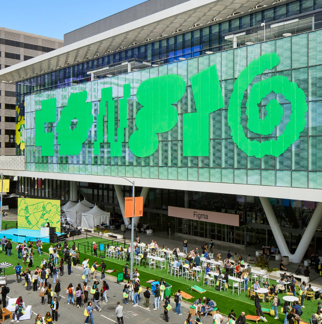 Crowd gathered outside the Moscone Center during a Figma event, with large green graphics covering the glass facade.