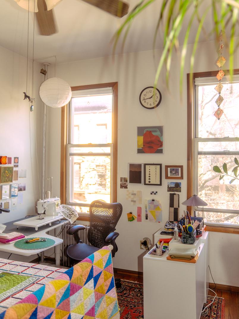 A photograph shows Nicole’s white desk, which holds her laptop and sewing machine. Artwork, color studies, and other inspiration dot her walls.