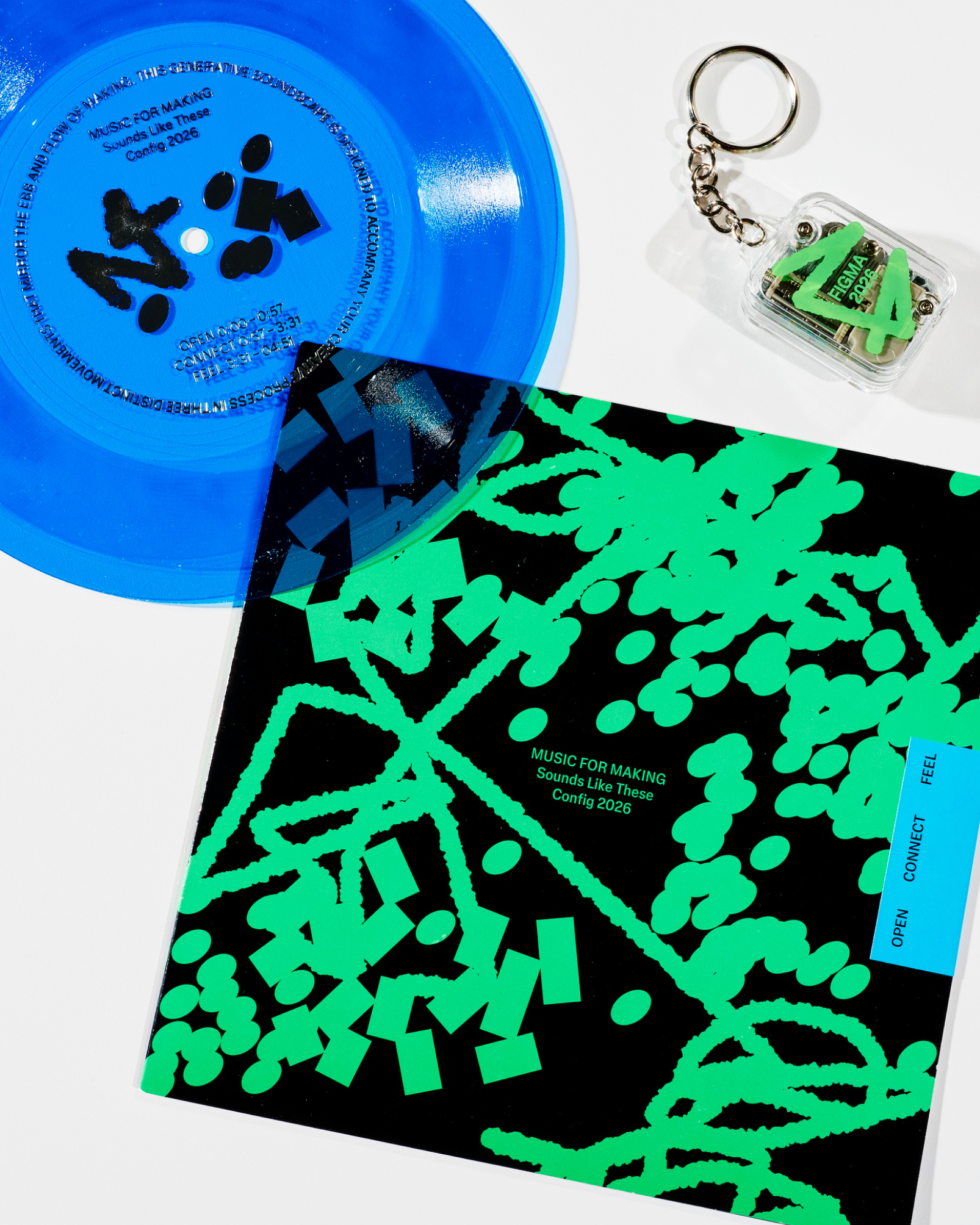 A blue translucent record, a green-and-black patterned record sleeve, and a Figma-branded keychain