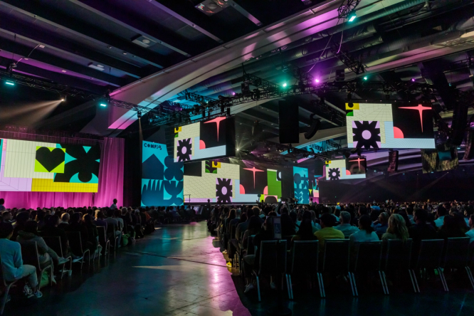Config 2023 main conference hall illuminated by various colorful screens with Config branding.