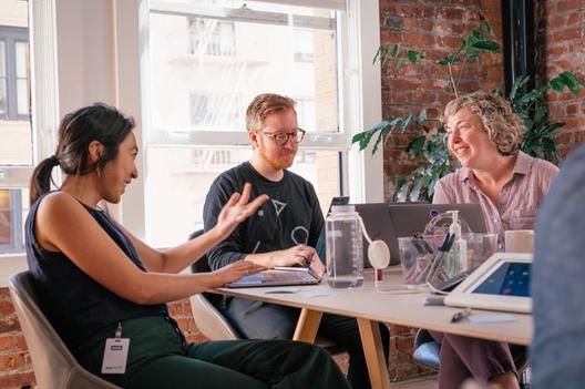 three people talking around a table