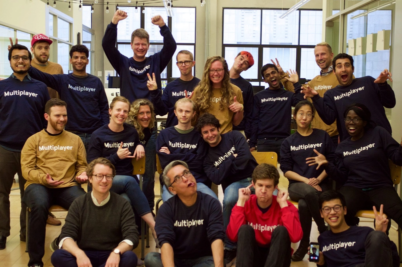 People in “Multiplayer” shirts pose for a photo with peace signs.