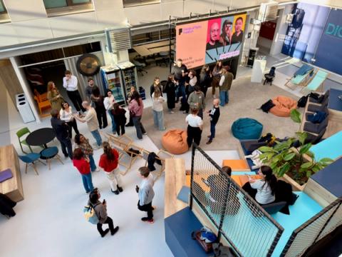 Attendees shot from above talk to each other in a bright venue at an event