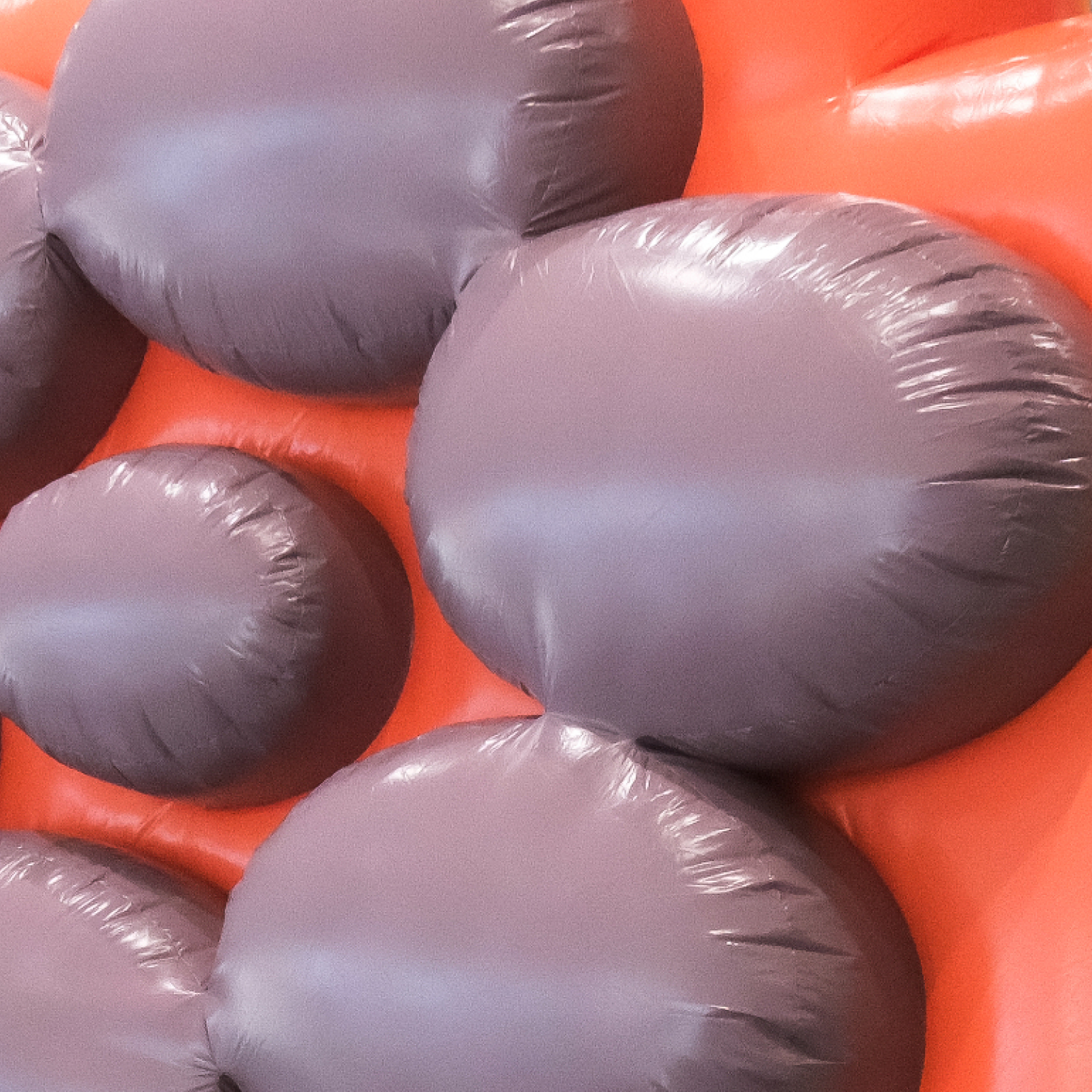 Cluster of large, rounded purple inflatables attached to an orange square background, viewed in close-up