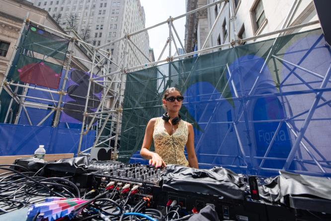 A DJ performs in front of scaffolding covered in Figma graphics during the outdoor event.