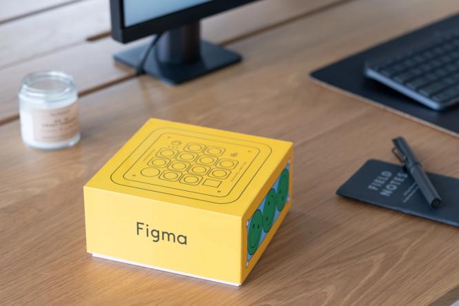 A yellow box that says "Figma" with an image of a keyoard on it, sitting on a desk.