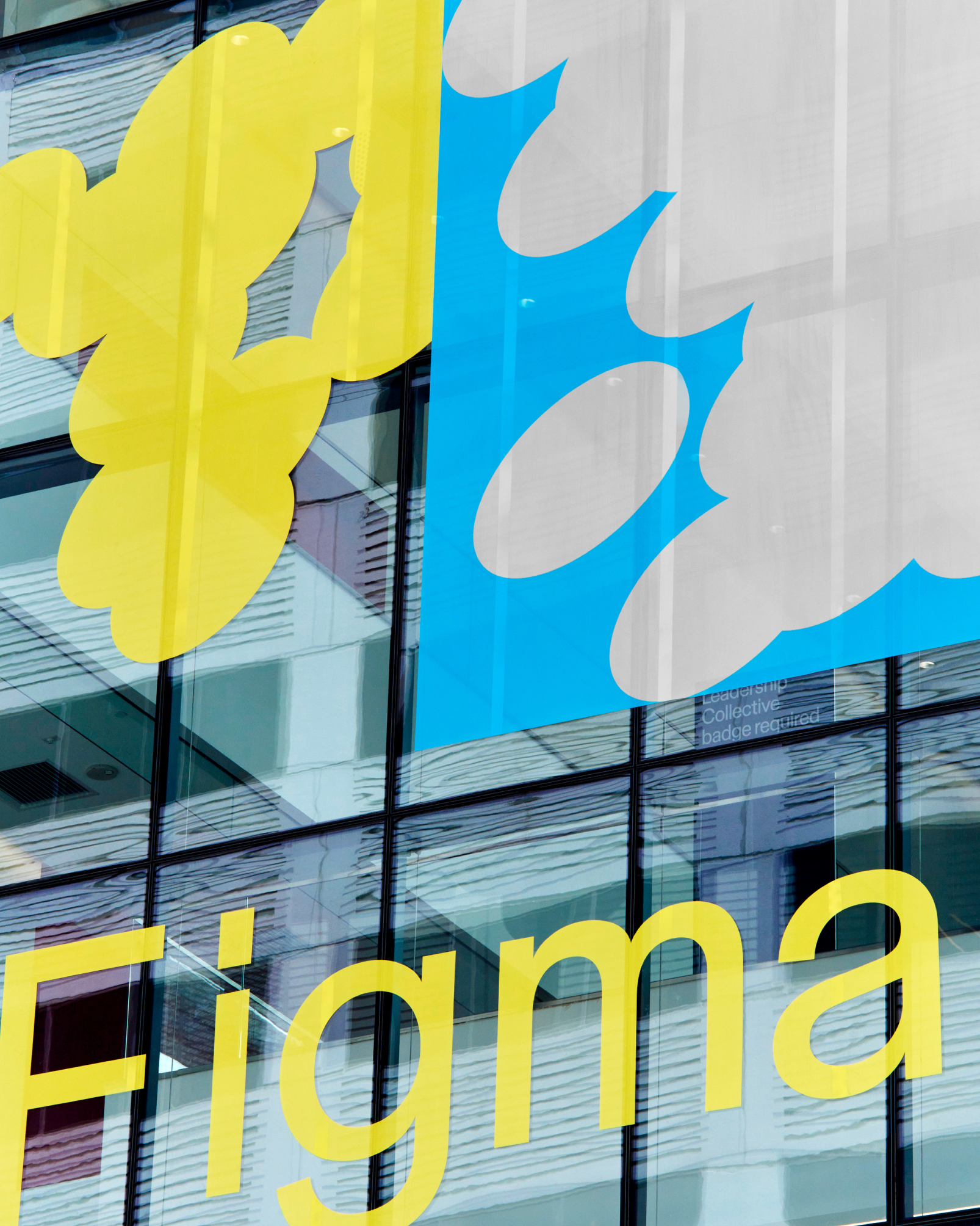 The Figma logo and oval graphics in yellow and blue are printed on the glass exterior of a building.