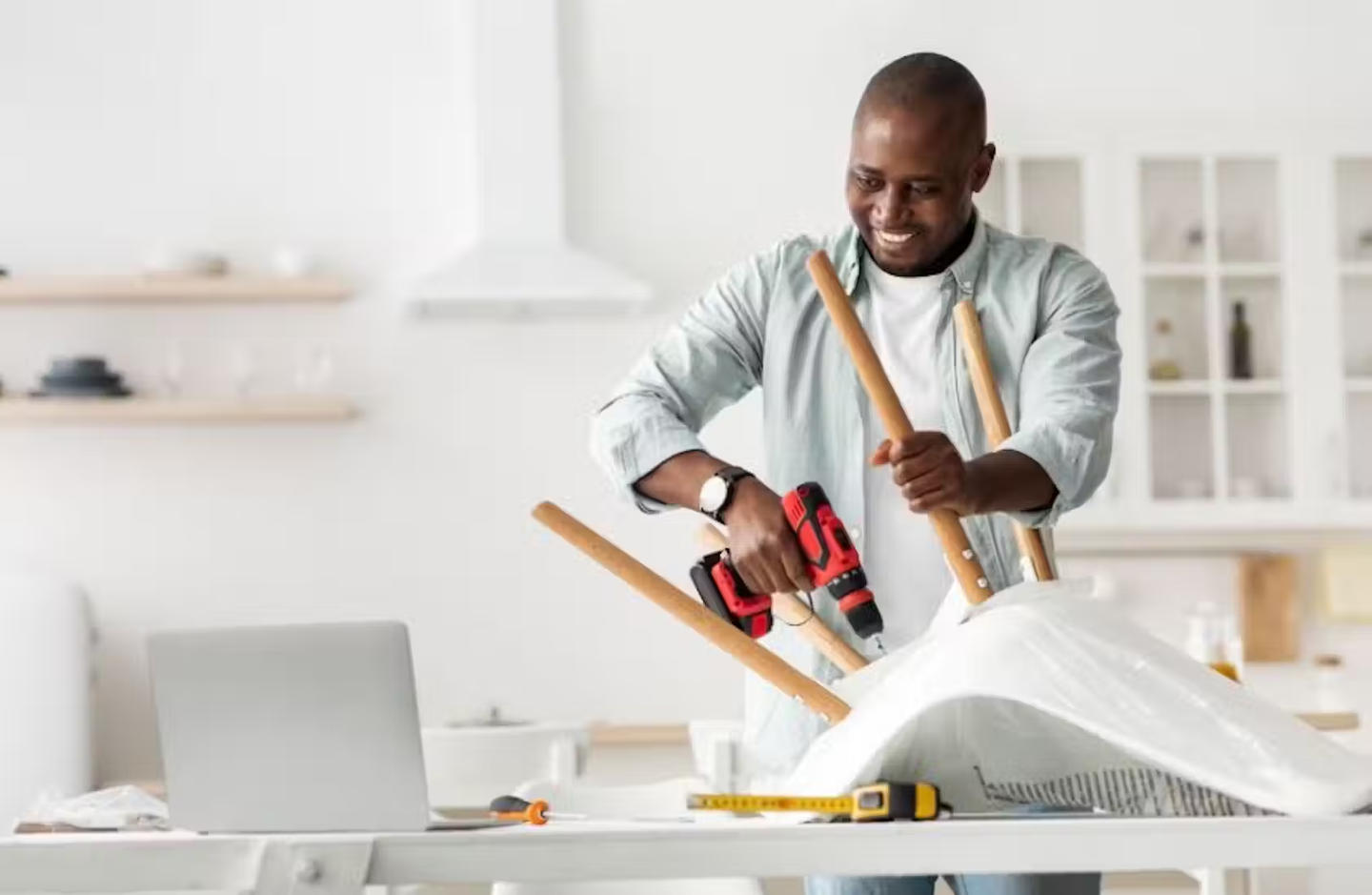 A man using a drill to put together some furniture.