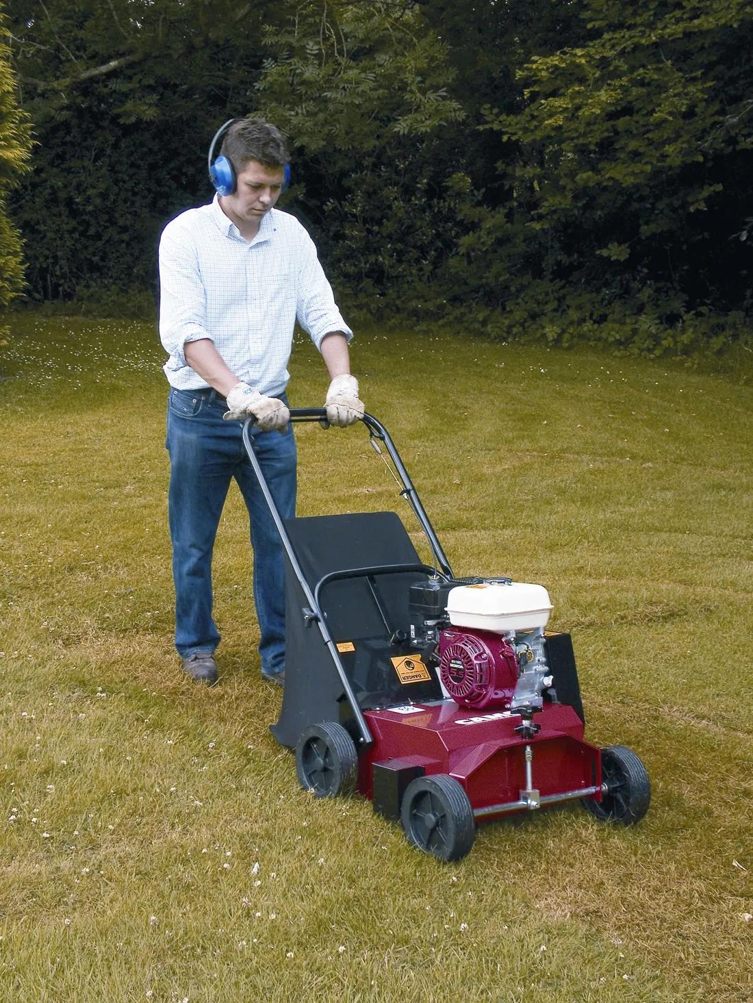 gardener pushing lawn scarifier