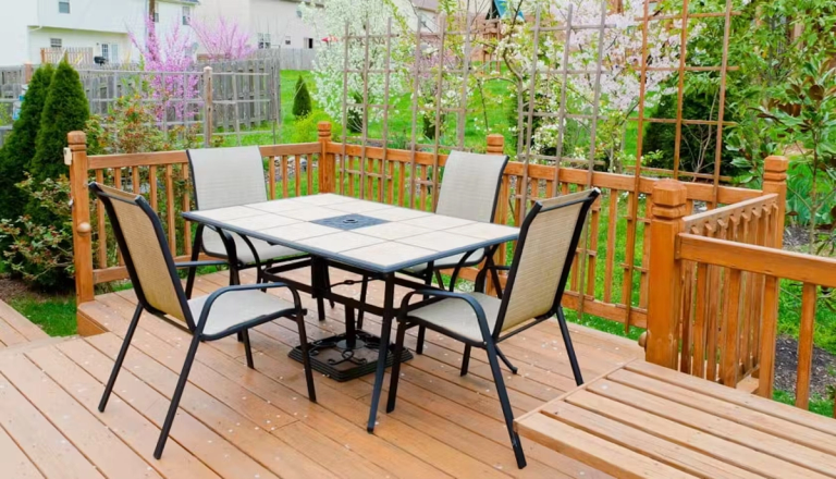 A back garden with decking, table and chairs.
