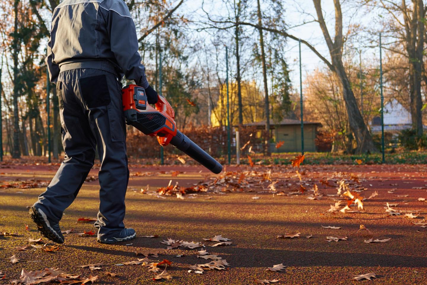 man cleaning ground using leaf blower