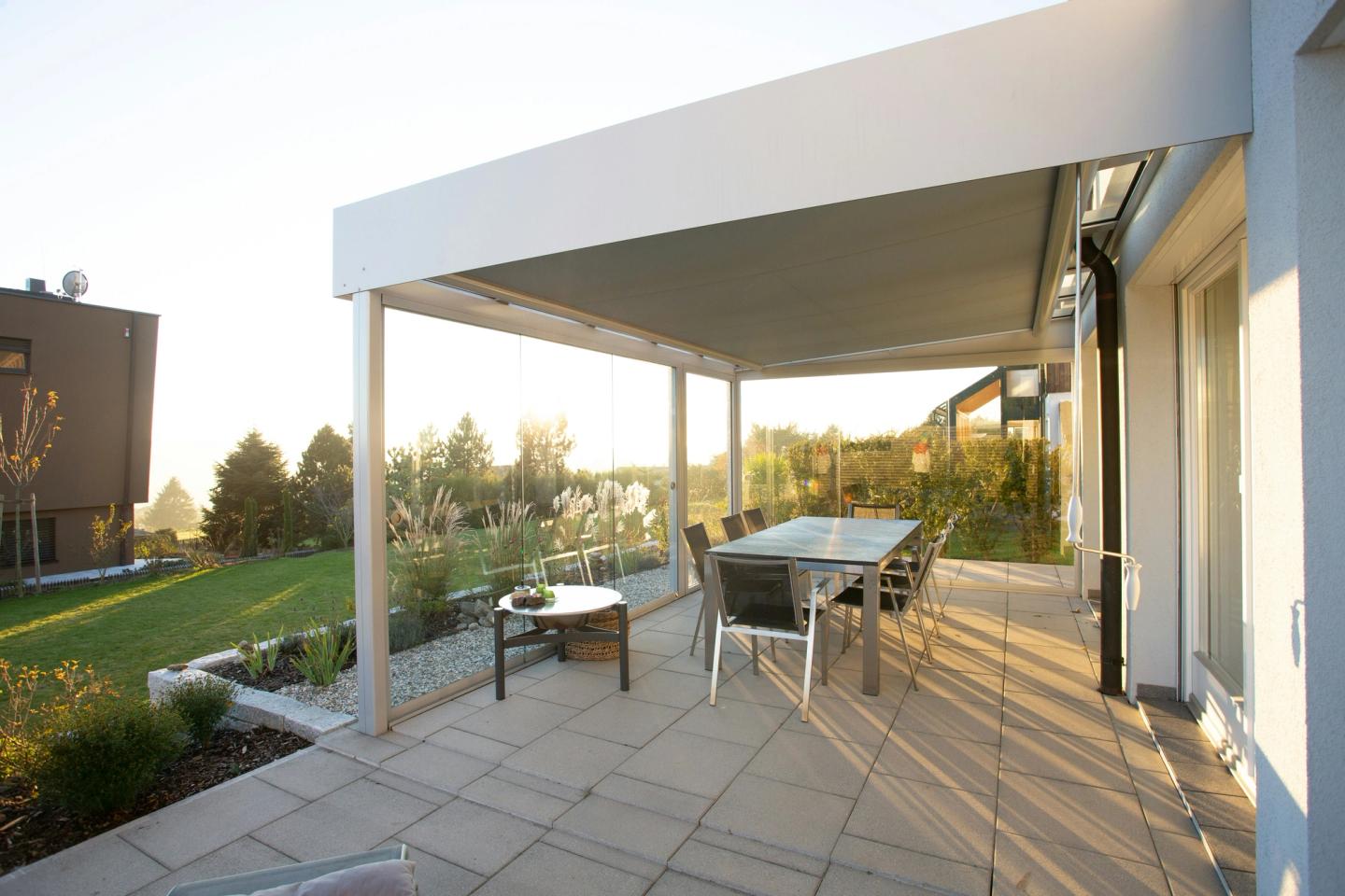 Finished paved patio with a dining table and chairs in low autumn sunlight
