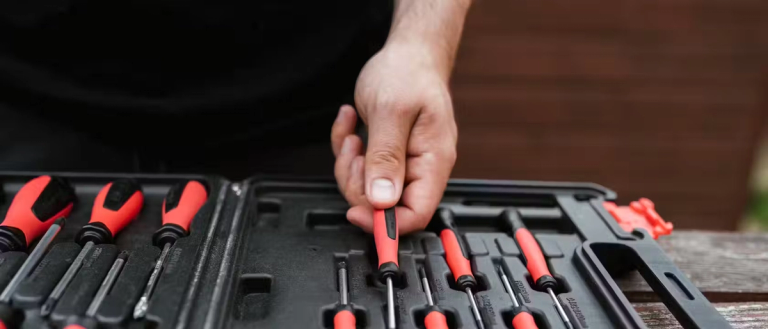 Someone choosing an insulated screwdriver from a tool kit.
