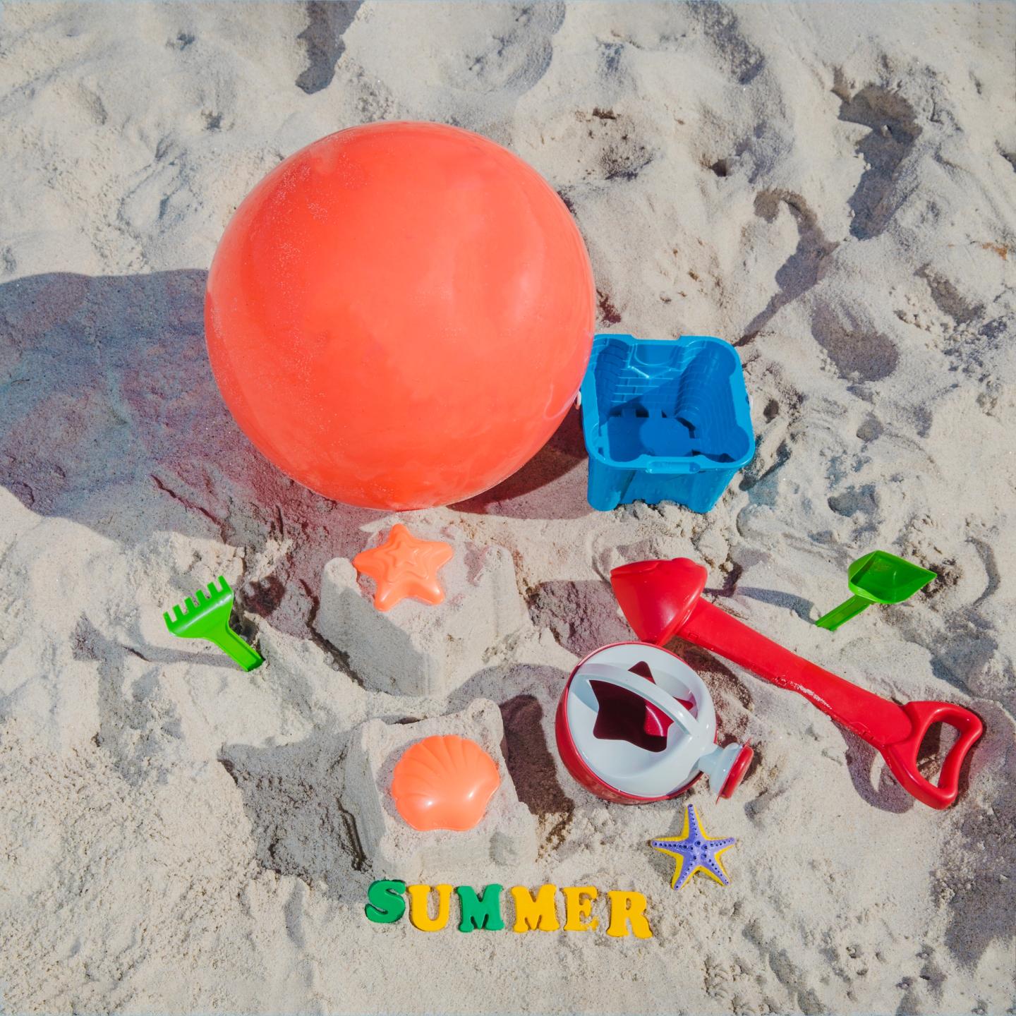 Different toys in the sand with green & yellow letters spelling out "Summer".