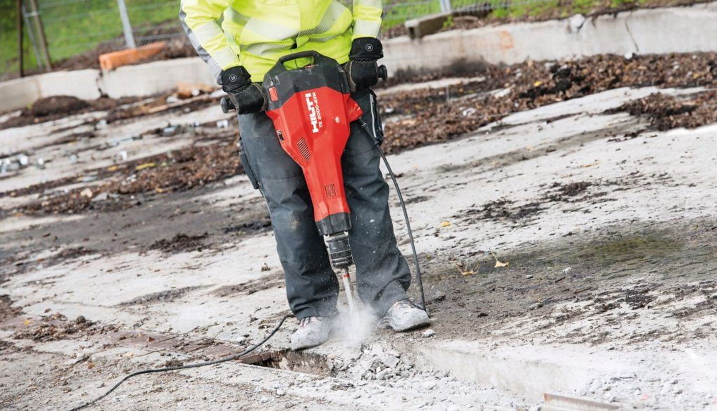 Operator in hi-vis breaking out a concrete slab with a Hilti breaker on a groundworks site