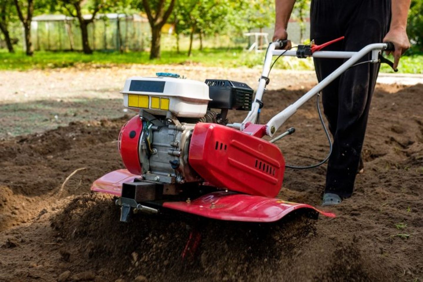 a person using power rotavator to prepare a new lawn