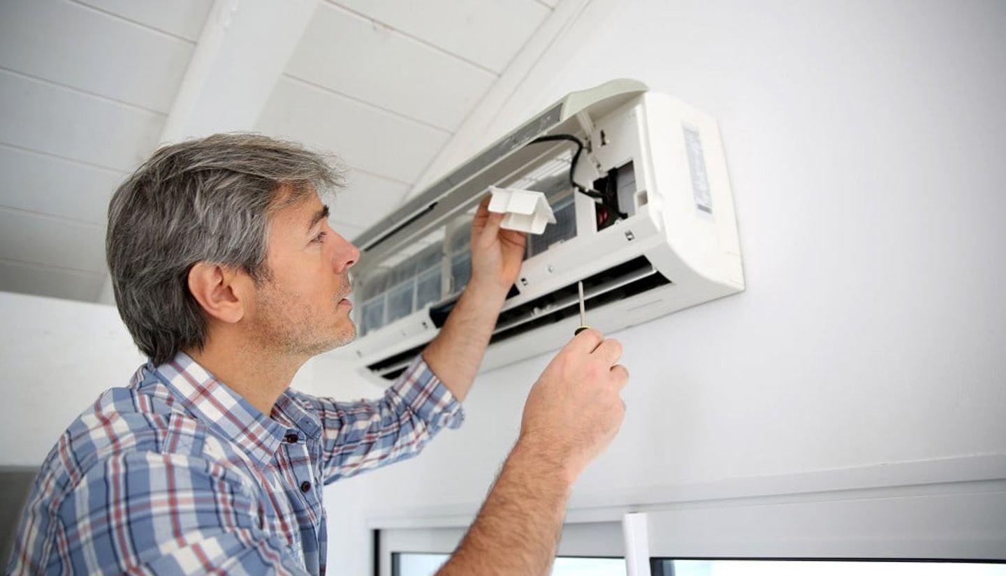 Man maintaining the air conditioner unit before turning it on