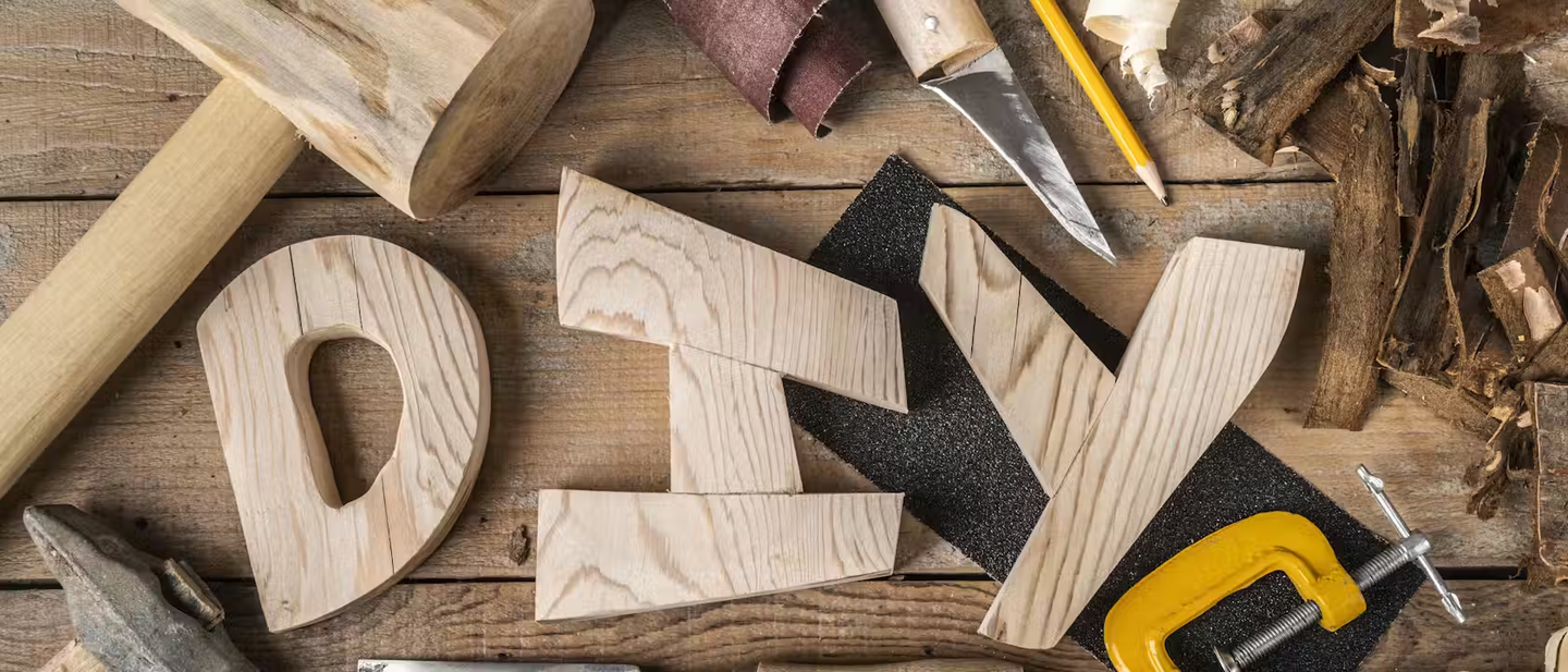 A range of hand tools surrounding wooden letters spelling out DIY