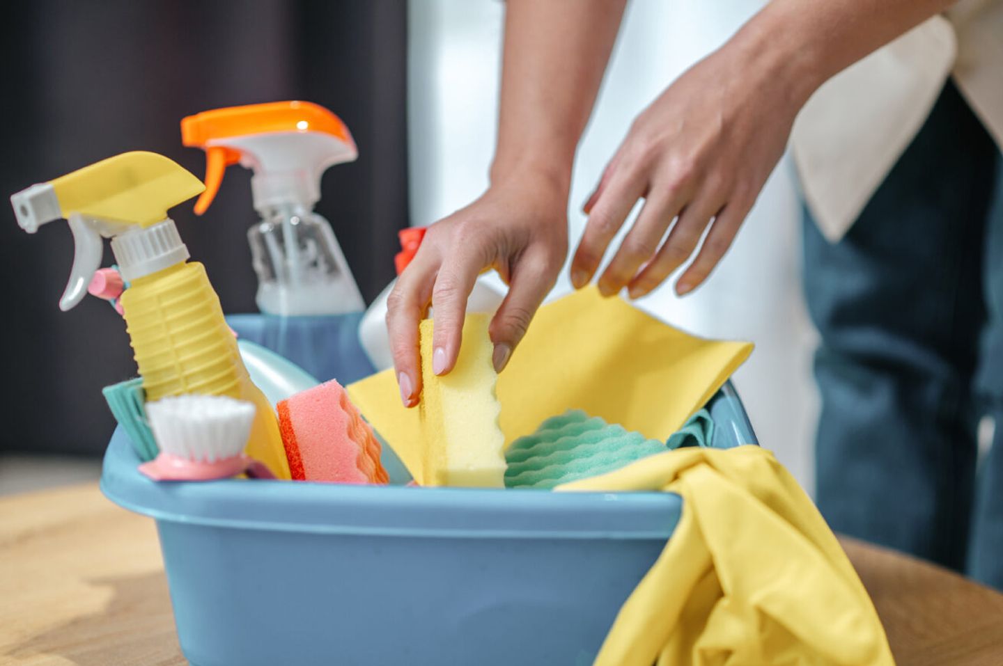 Bowl with cleaning products sprays cloths sponges brush