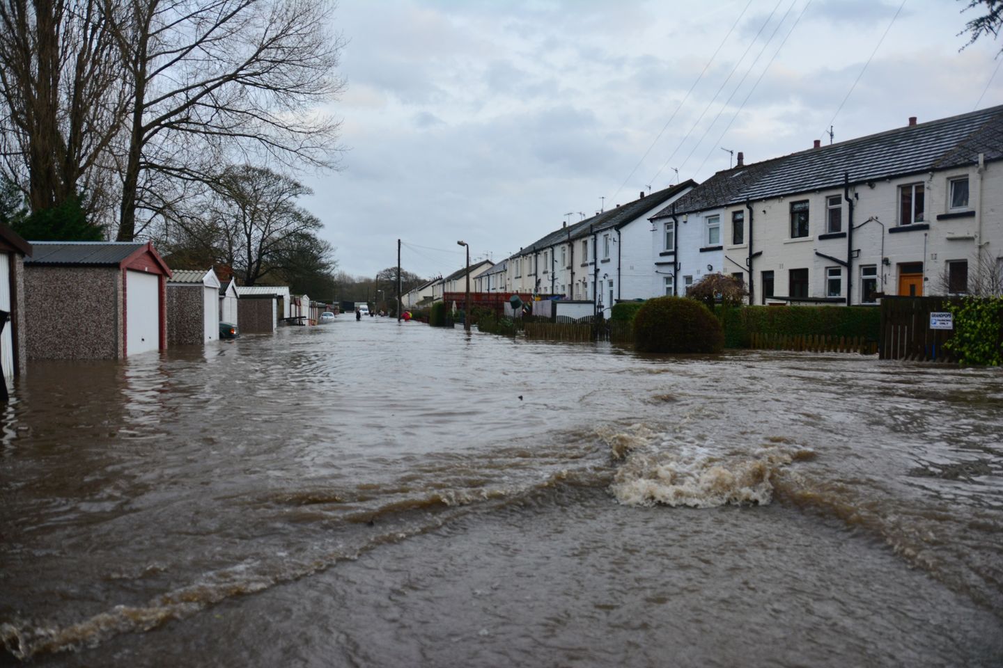 A flooded British street with garages and tarraced houses