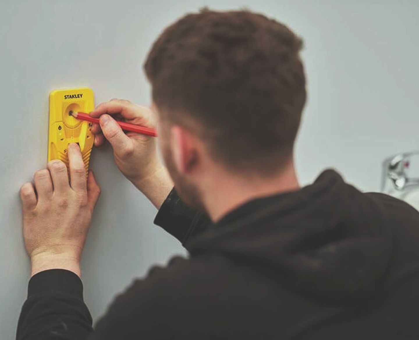 Using a stud, metal and live wire detector to mark a wall before cutting into it