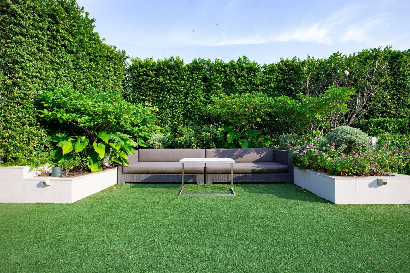 a modern garden minimalistic garden couch surrounded by garden plants and hedge