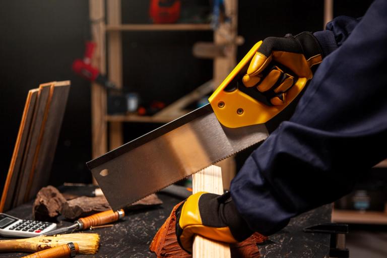 person sawing a piece of timber