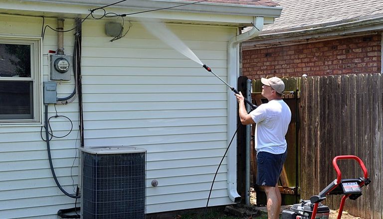 man cleaning house using a pressure washer