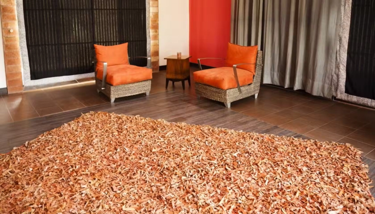 Two orange chairs and an orange rug on a tiled floor.
