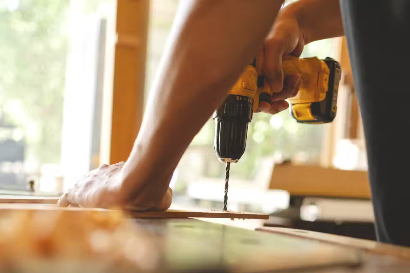 Someone using a cordless drill on a plank of wood.