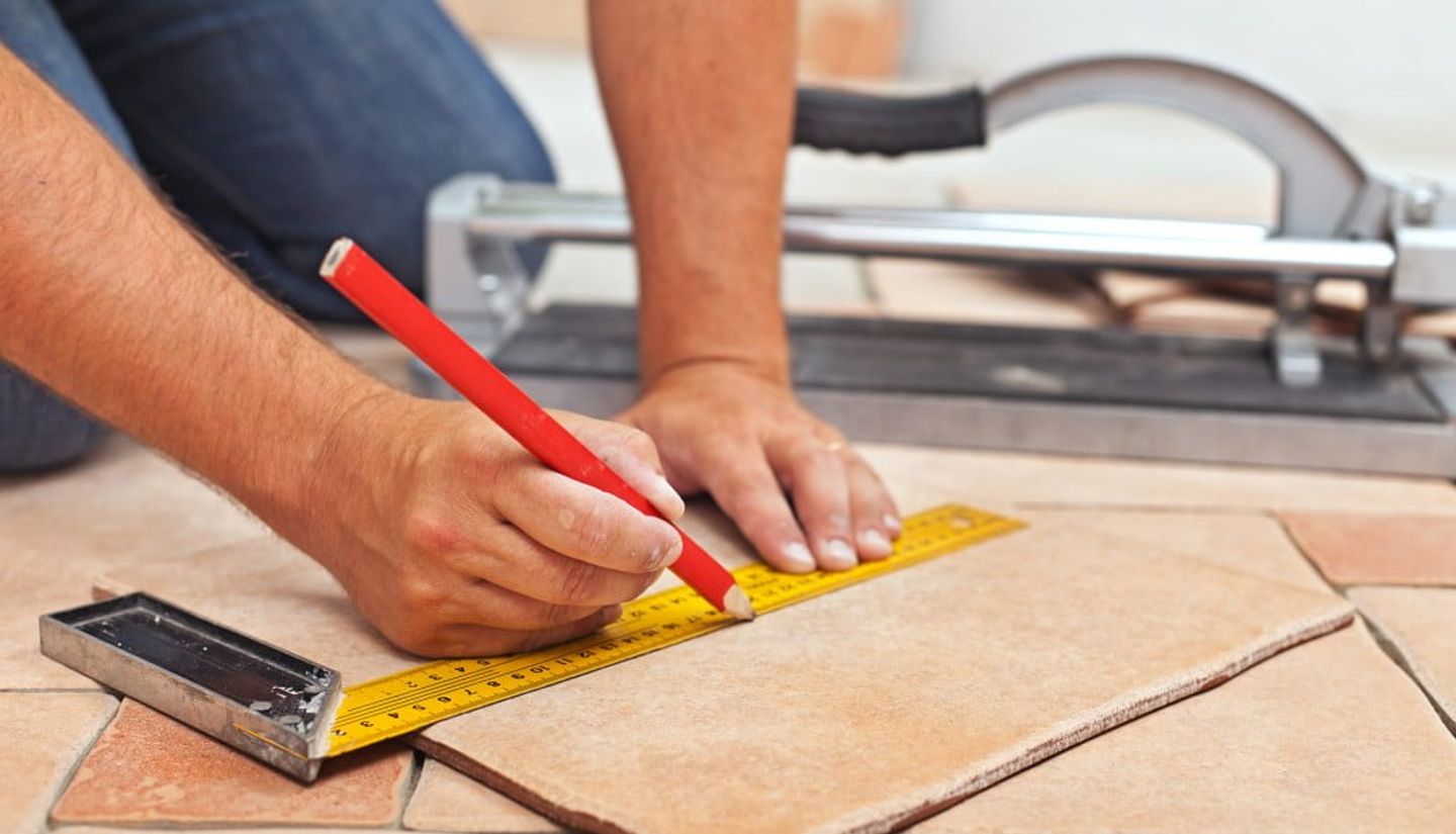 person marking tile to cut