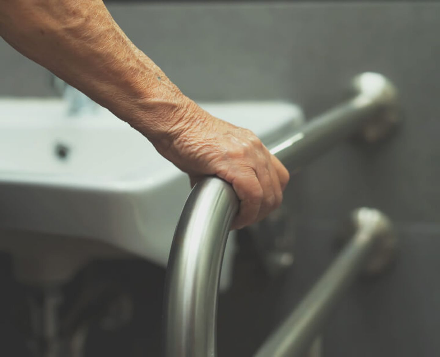 Someone holding on to a grab rail in a bathroom.