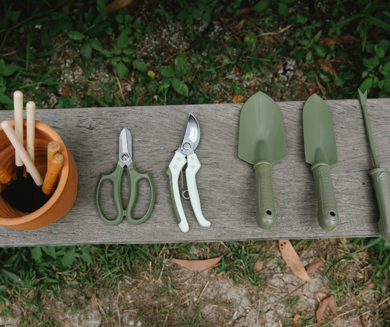 a pot with garden hand tools pruning scissors secateurs set of garden spades lying on the bench 