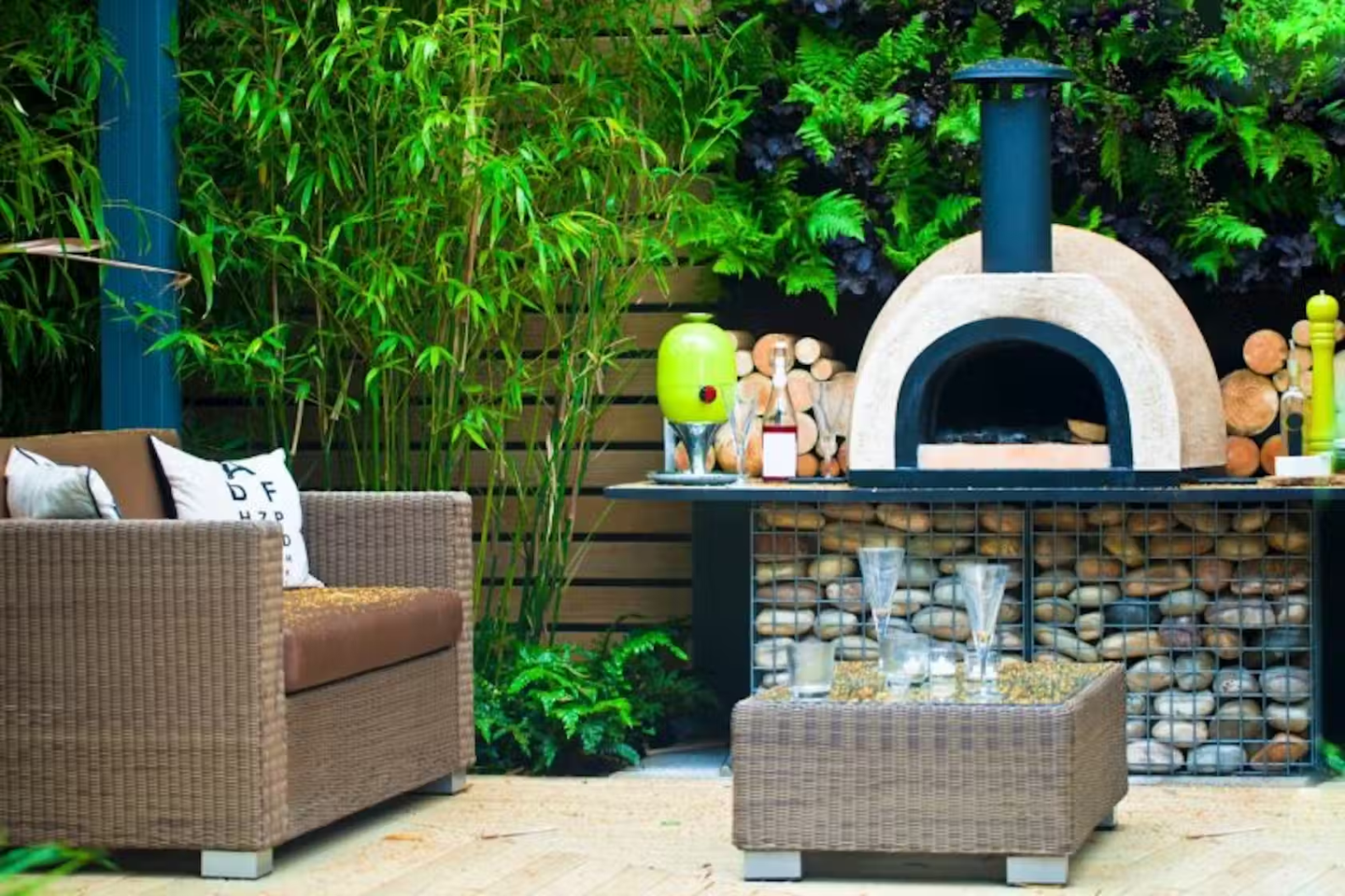 Back garden area with decking, table, chair and a wood-fired oven.