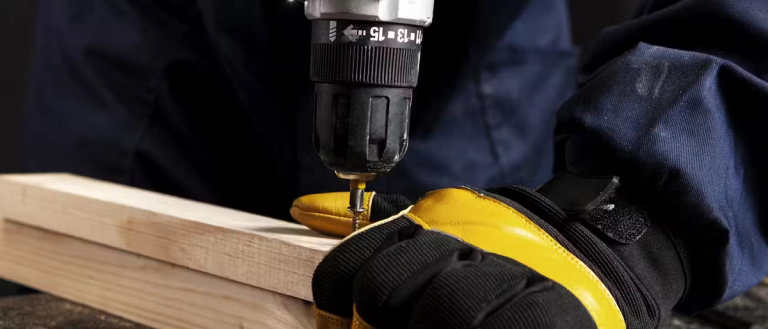 A power drill putting a screw in planks of wood.
