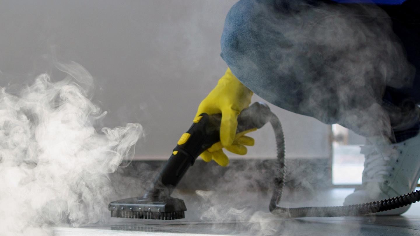 professional cleaning service person using steam cleaner office