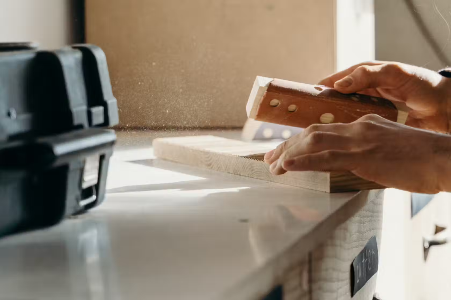 Someone sanding wood with a sanding block.