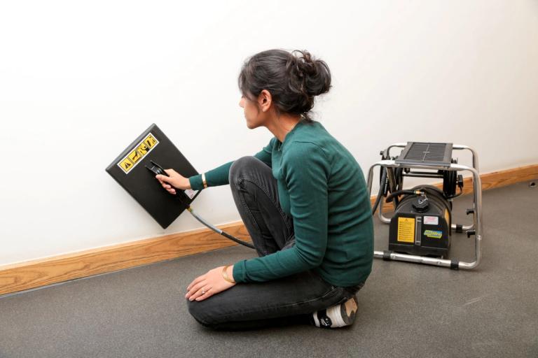 Woman stripping wallpaper using steamer wallpaper remover