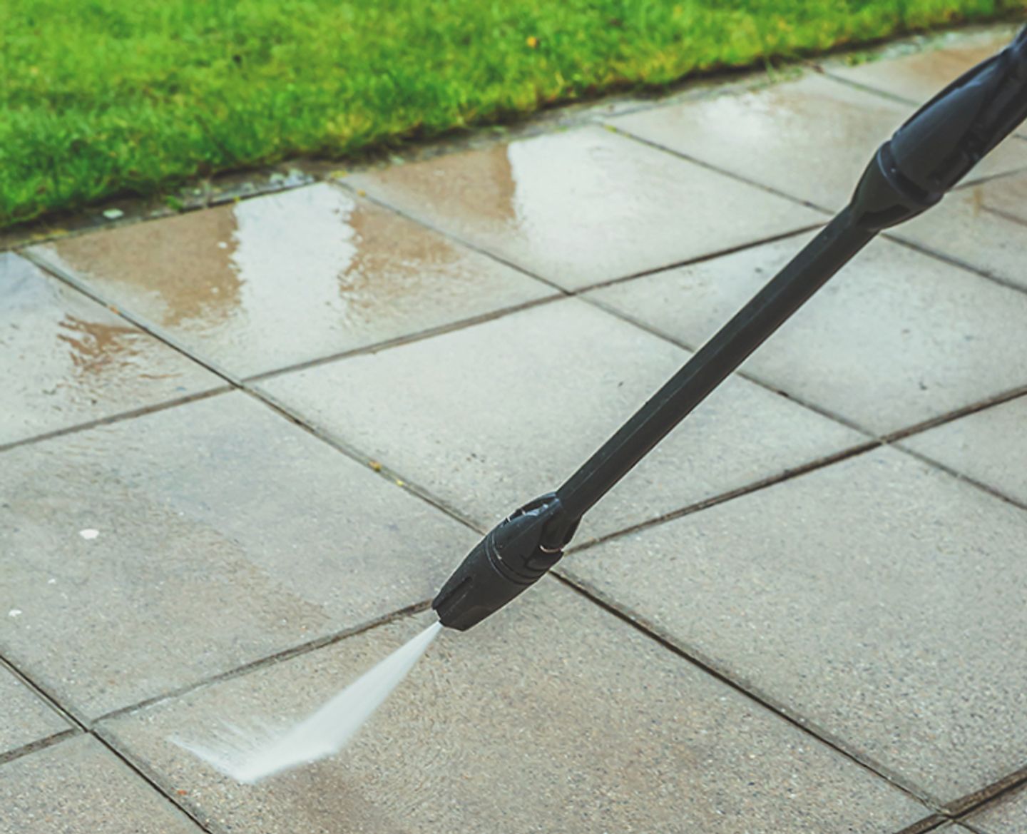 A pressure washer being used on paving.