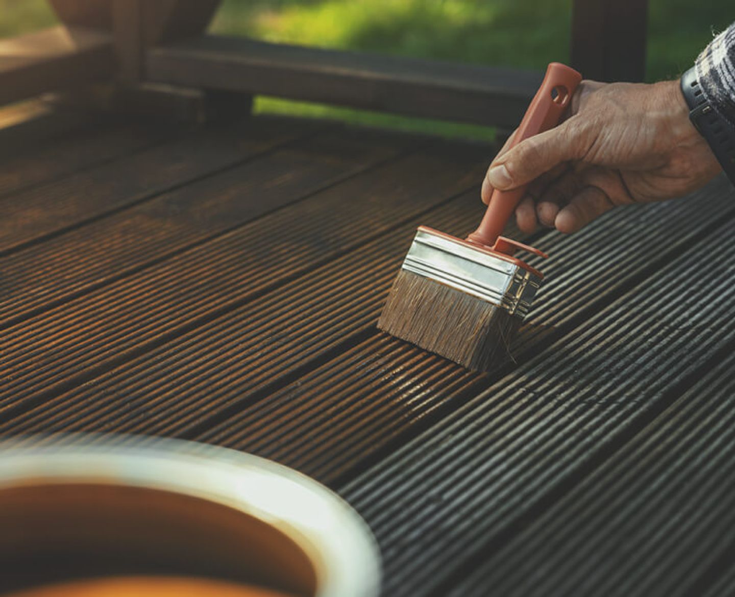 Someone applying stain to a decking area.