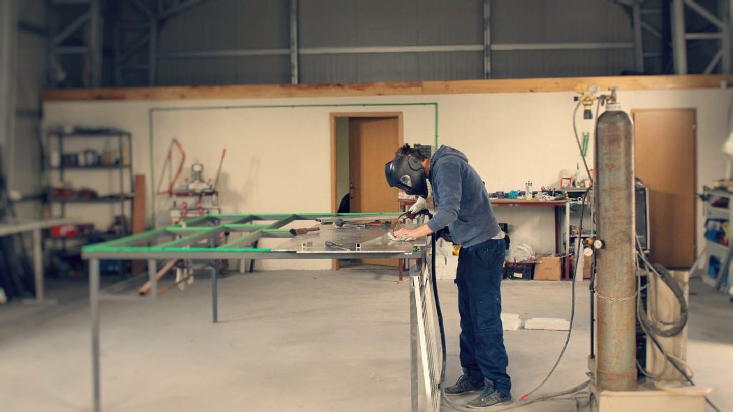 person in a welding mask welding a piece of metal