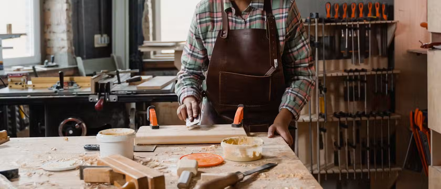 Someone sanding a piece of wood on a workstation.