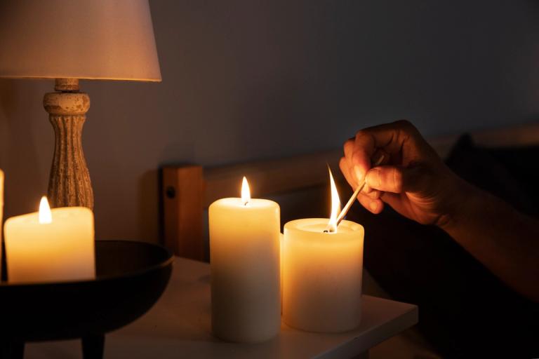 Someone lighting candles by the bedside during a power cut.